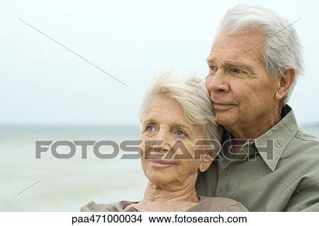 Senior couple outdoors, smiling and looking away, close-up View Large Photo Image Picture - Senior couple outdoors, smiling and looking away, close-up. Fotosearch