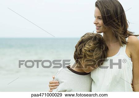 Teenage girl standing on beach looking away, younger brother leaning his head on her shoulder View Large Photo Image Stock Photo - Teenage girl standing on beach looking away, younger brother leaning his head on her shoulder. Fotosearch