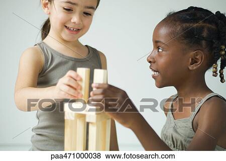Two girls playing with building blocks together, both smiling View Large Photo Image Stock Photo - Two girls playing with building blocks together, both smiling. Fotosearch