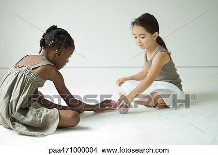 Two girls sitting on the floor playing with toy balls View Large Photo Image Picture - Two girls sitting on the floor playing with toy balls. Fotosearch