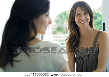 Two women sitting together, smiling, looking away View Large Photo Image Stock Image - Two women sitting together, smiling, looking away. Fotosearch