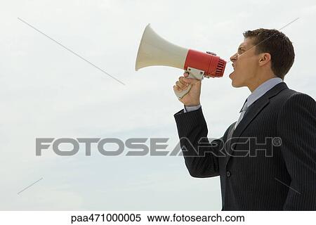 Young businessman shouting into megaphone, side view View Large Photo Image Stock Photography - Young businessman shouting into megaphone, side view. Fotosearch