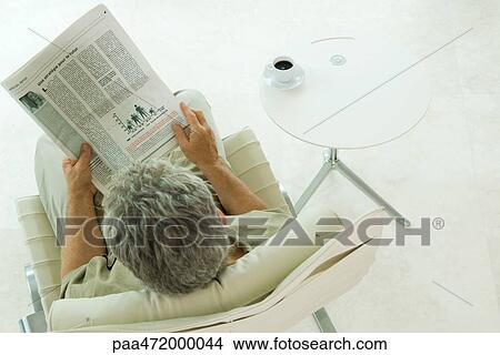 Man sitting, reading newspaper, high angle view View Large Photo Image Picture - Man sitting, reading newspaper, high angle view. Fotosearch