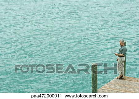 Man standing on dock listening to mp3 player, high angle view View Large Photo Image Stock Image - Man standing on dock listening to mp3 player, high angle view. Fotosearch