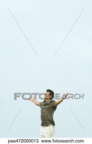 Man standing outdoors with eyes closed, arms out, smiling View Large Photo Image Stock Image - Man standing outdoors with eyes closed, arms out, smiling. Fotosearch