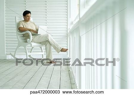 Man using laptop computer on porch View Large Photo Image Stock Image - Man using laptop computer on porch. Fotosearch