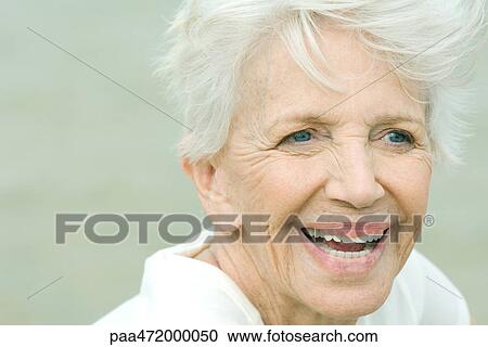 Stock Image - Senior woman smiling, looking away, portrait. Fotosearch