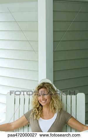 Woman sitting in chair smiling, looking away View Large Photo Image Stock Photo - Woman sitting in chair smiling, looking away. Fotosearch