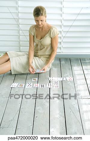 Stock Image - Woman sitting on deck playing cards. Fotosearch