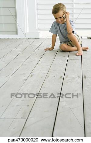 Boy sitting on deck listening to seashell View Large Photo Image Stock Image - Boy sitting on deck listening to seashell. Fotosearch