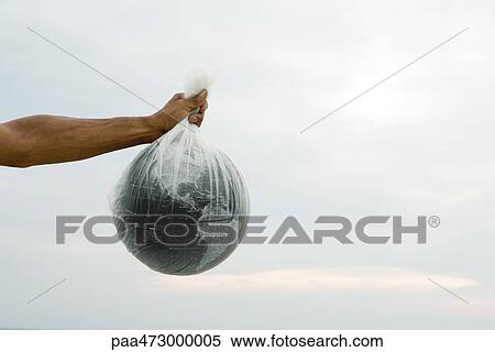 Stock Photography - Cropped view of arm holding globe in plastic bag. Fotosearch