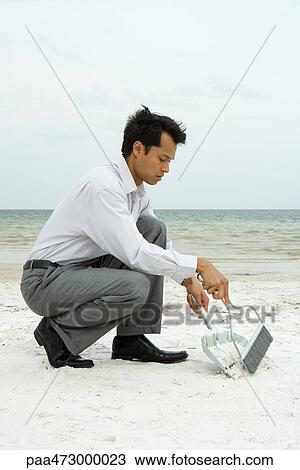 Man crouching on beach using broom and dustpan View Large Photo Image Stock Image - Man crouching on beach using broom and dustpan. Fotosearch