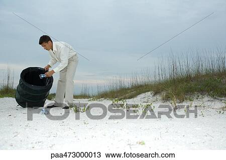 Man digging through trash can on beach, removing plastic bottles View Large Photo Image Stock Image - Man digging through trash can on beach, removing plastic bottles. Fotosearch