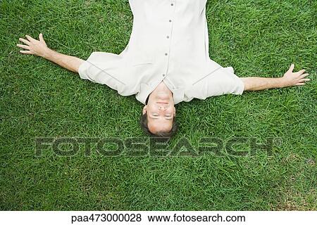 Man lying on back on grass, smiling at camera, viewed from directly above View Large Photo Image Stock Photo - Man lying on back on grass, smiling at camera, viewed from directly above. Fotosearch