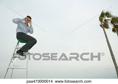 Man sitting on top of ladder looking through binoculars View Large Photo Image Picture - Man sitting on top of ladder looking through binoculars. Fotosearch
