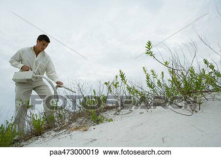 Man standing on sand dune holding vacuum cleaner View Large Photo Image Stock Photo - Man standing on sand dune holding vacuum cleaner. Fotosearch