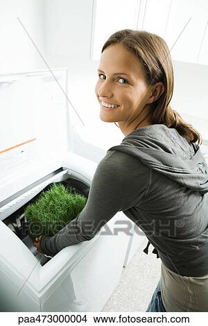 Teenage girl placing grass in washing machine, smiling over shoulder at camera View Large Photo Image Picture - Teenage girl placing grass in washing machine, smiling over shoulder at camera. Fotosearch