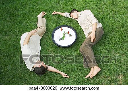 Two men lying on grass around bowl with flower, eyes closed View Large Photo Image Stock Photograph - Two men lying on grass around bowl with flower, eyes closed. Fotosearch