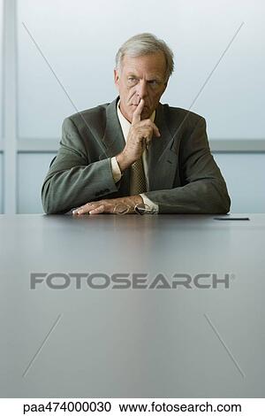 Businessman holding finger to lips, looking away View Large Photo Image Stock Image - Businessman holding finger to lips, looking away. Fotosearch