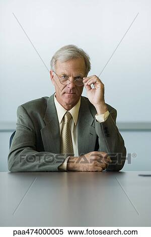 Stock Photography - Businessman looking over the top of his glasses at camera. Fotosearch