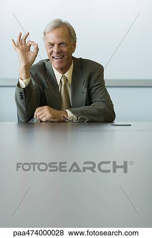 Businessman making OK hand gesture and smiling at camera View Large Photo Image Stock Photo - Businessman making OK hand gesture and smiling at camera. Fotosearch