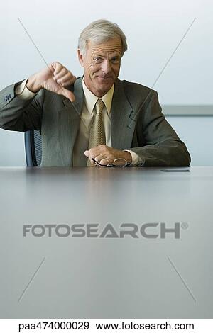 Stock Photo - Businessman making thumbs down gesture, smiling at camera. Fotosearch
