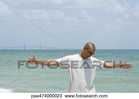 Man Standing At The Beach With Arms Outstretched Looking