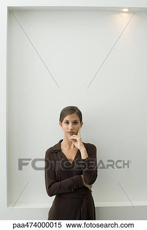 Teenage girl standing with arms folded, hand under chin, looking at camera View Large Photo Image Stock Photography - Teenage girl standing with arms folded, hand under chin, looking at camera. Fotosearch