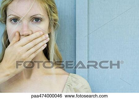 Stock Photograph - Woman covering mouth with hand, looking at camera. Fotosearch