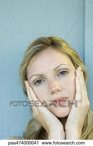 Stock Image - Woman holding face, looking at camera. Fotosearch