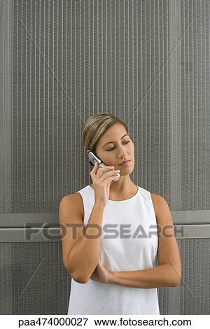 Woman holding up cell phone, looking away View Large Photo Image Stock Photo - Woman holding up cell phone, looking away. Fotosearch