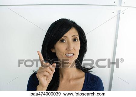 Woman holding up finger, looking at camera View Large Photo Image Stock Photo - Woman holding up finger, looking at camera. Fotosearch