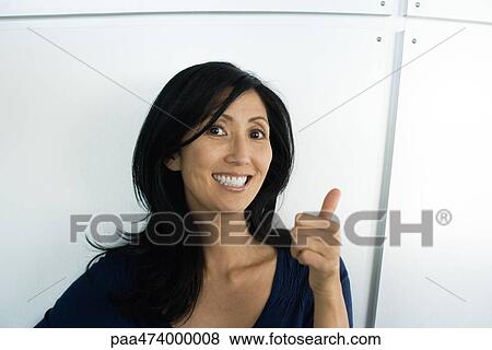Woman making thumbs up gesture and smiling at camera View Large Photo Image Stock Photo - Woman making thumbs up gesture and smiling at camera. Fotosearch
