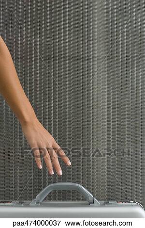 Stock Photo - Woman picking up briefcase, cropped view of hand. Fotosearch