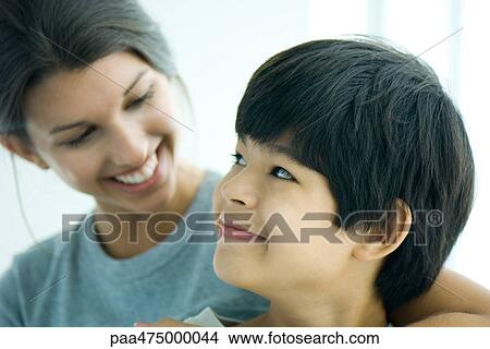 Picture - Boy looking over shoulder at sister, both smiling. Fotosearch