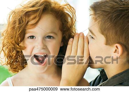 Boy whispering in girl's ear, close-up View Large Photo Image Stock Photo - Boy whispering in girl's ear, close-up. Fotosearch