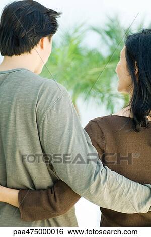 Couple standing with arms around each other, rear view View Large Photo Image Stock Photograph - Couple standing with arms around each other, rear view. Fotosearch