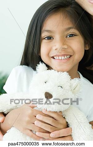 Girl holding teddy bear, smiling at camera View Large Photo Image Stock Photography - Girl holding teddy bear, smiling at camera. Fotosearch
