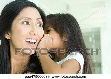 Girl whispering in mother's ear, close-up View Large Photo Image Stock Photo - Girl whispering in mother's ear, close-up. Fotosearch