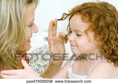 Mother and daughter touching each other's hair, both smiling View Large Photo Image Stock Photo - Mother and daughter touching each other's hair, both smiling. Fotosearch