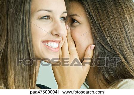Teenage girl whispering in twin sister's ear, close-up View Large Photo Image Stock Image - Teenage girl whispering in twin sister's ear, close-up. Fotosearch