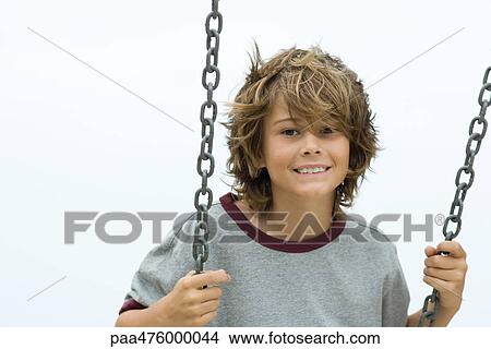 Boy on swing smiling at camera, portrait View Large Photo Image Picture - Boy on swing smiling at camera, portrait. Fotosearch