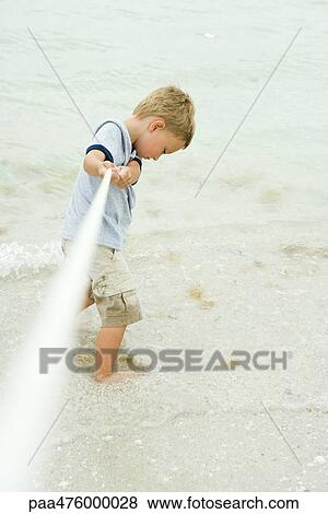 Boy playing tug-of-war at the beach, looking down View Large Photo Image Stock Photo - Boy playing tug-of-war at the beach, looking down. Fotosearch