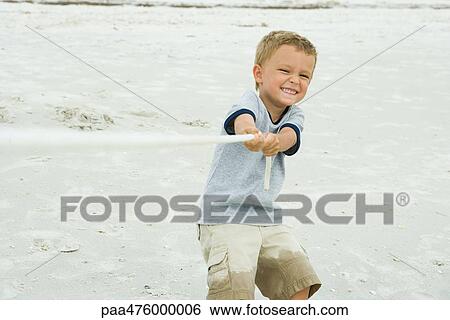 Stock Photograph - Boy playing tug-of-war, smiling at camera. Fotosearch