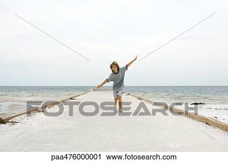 Boy running at the beach with arms outstretched, front view View Large Photo Image Stock Image - Boy running at the beach with arms outstretched, front view. Fotosearch