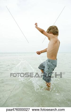 Boy splashing ankle-deep in water, side view View Large Photo Image Stock Photo - Boy splashing ankle-deep in water, side view. Fotosearch