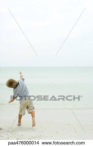 Child running on beach toward ocean, rear view View Large Photo Image Picture - Child running on beach toward ocean, rear view. Fotosearch