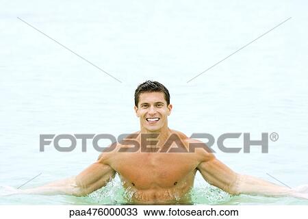Stock Image - Man in swimming pool, smiling at camera, portrait. Fotosearch