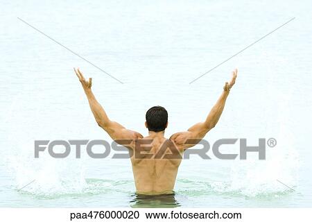Muscular man standing in swimming pool with arms raised, rear view View Large Photo Image Stock Image - Muscular man standing in swimming pool with arms raised, rear view. Fotosearch