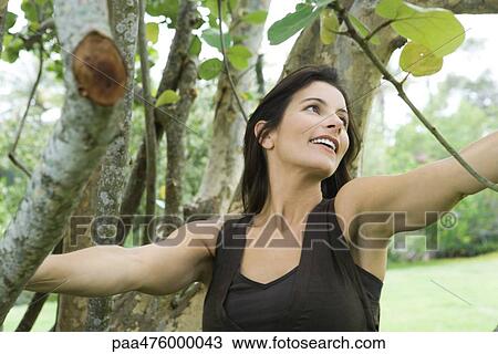 Woman among trees, smiling, looking away View Large Photo Image Stock Image - Woman among trees, smiling, looking away. Fotosearch